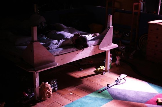 Une chambre en clair obscur, avec un lit en bois.