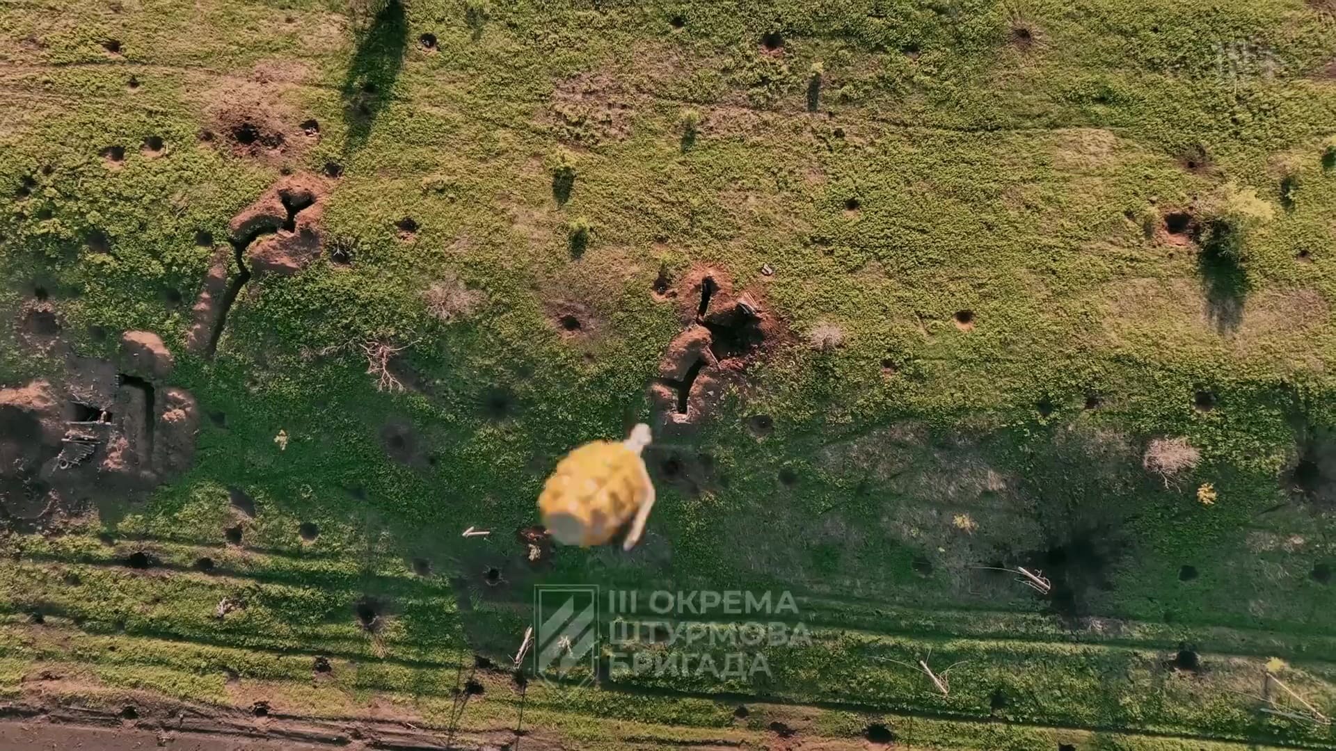 Vus plonfeante sur une grenade floue qui tombe vers le sol. Plusieurs trous sont déjà discernables au sol, et de l'herbe ailleurs.