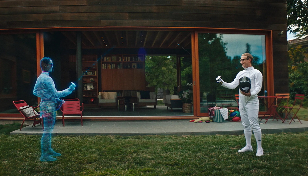 Dans un jardin, devant une baie vitrée, deux personnes en tenue blanche d'escrime se font face. Sur la droite, Mark Zuckerberg, sur la gauche, un hologramme.