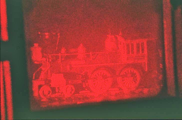 Une locomotive se détache en rouge vif sur un fond rouge foncé.